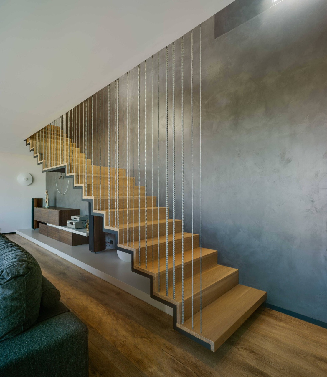Escalera de madera con barandilla de cables de acero verticales en Villa Apiarum, diseño interior de tomas amat estudio de arquitectura con trasdós en tecnocemento.