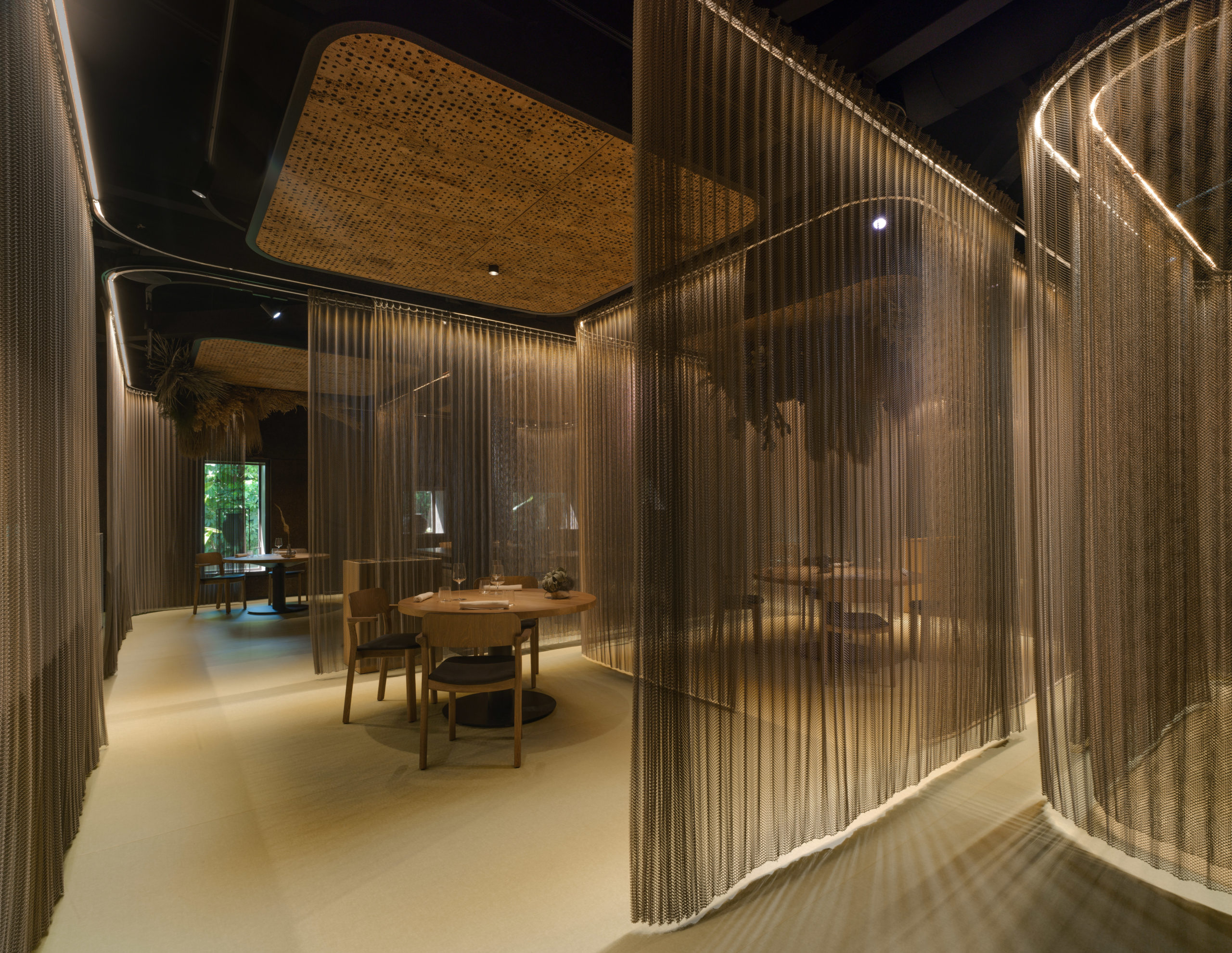 Vista general de la sala del Restaurante La Finca Elche con cortinas de aluminio se adaptan a las curvas y acotan la porción techo de corcho con motivo vegetalSala interior Restaurante La Finca en Elche con cortinas de aluminio curvas — estudio de arquitectura Alicante tamatestudio